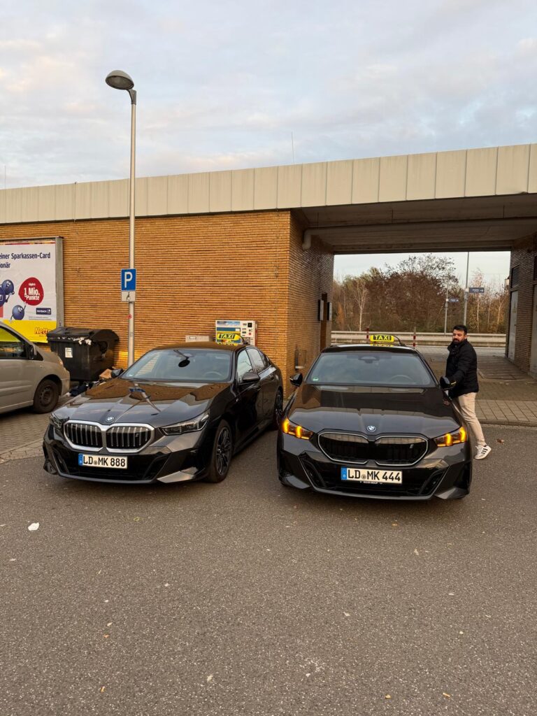 2 black Mk taxibetreib landau taxi parked . one is BMW black and other is mercedes black