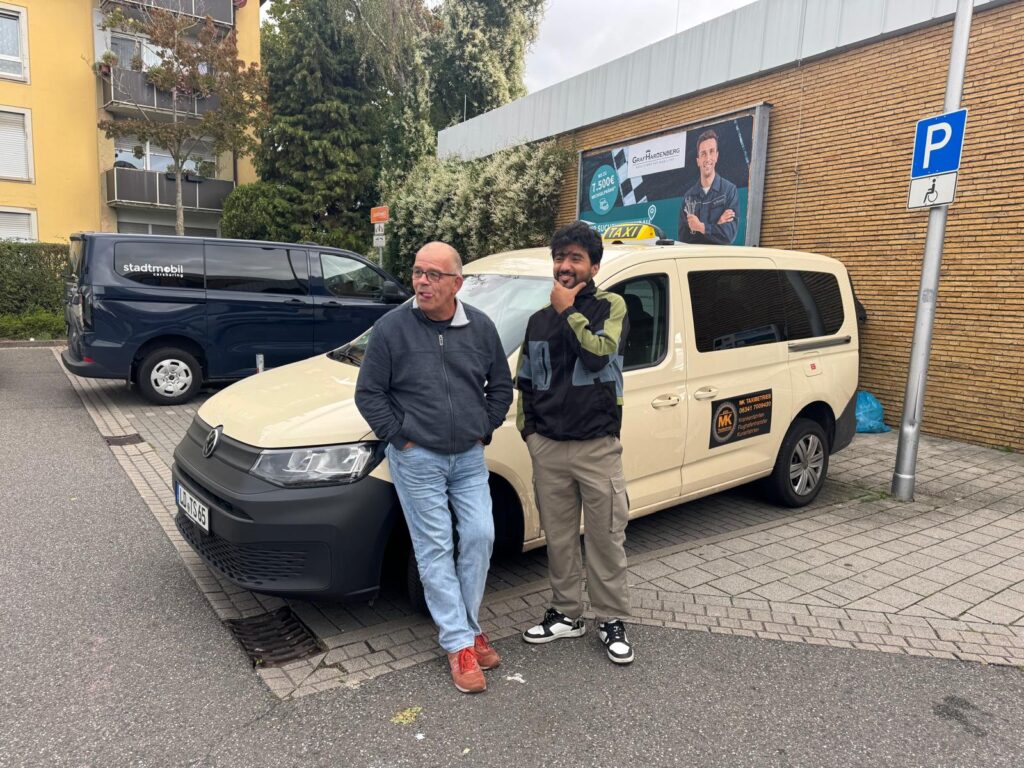 2 MK professional standing infront of MK taxi wheelchair